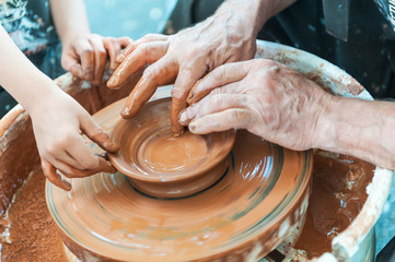 Handcrafted, Hands make clay. Master teaches the student to make pitcher on pottery wheel.