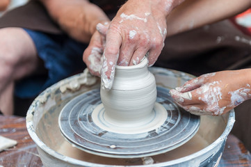 Handcrafted, Hands make clay. Master teaches the student to make pitcher on pottery wheel.