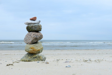 Fototapeta na wymiar Zen an einem Strand und das Meer im Hintergrund