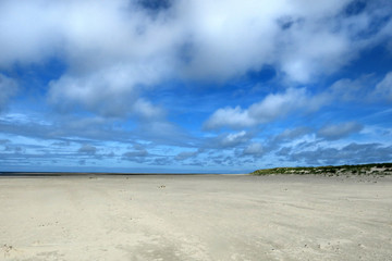 Fototapeta na wymiar Blauer Himmel mit weißen Wolken an einem Strand