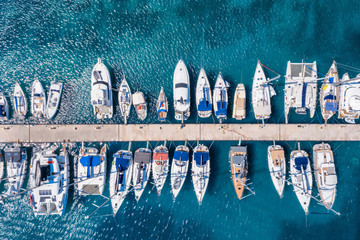 Luftaufnahme einer Marina mit zahlreichen Segelbooten und Yachten über türkisblauem Meer