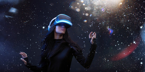 Fototapeta na wymiar Beautiful woman with flowing hair in futuristic dress over dark magic light background. Girl in glasses of virtual reality. Augmented reality, game, future technology concept. VR.