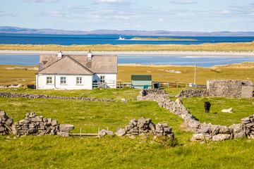 Farm house and field with stone walls and beach, Galway bay in background