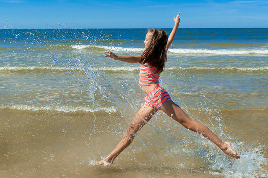 Beautiful girl running and jumping on the beach