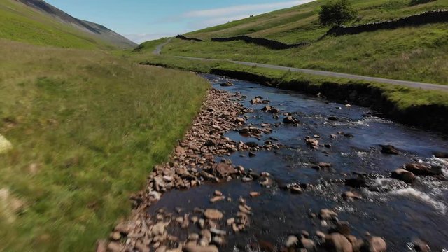 A low altitude, moderate speed flyover of Barbon Beck, Carnforth, Lancashire, England. This stunning countryside features a stream running alongside a small country lane.