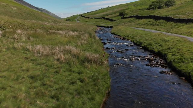 A low altitude, slow speed flyover of Barbon Beck, Carnforth, Lancashire, England. This stunning countryside features a stream running alongside a small country lane.