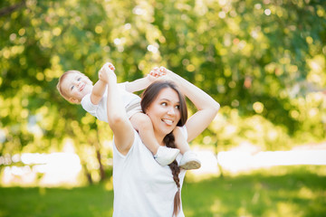 Obraz premium Mom plays with adorable baby son in park on grass. Sunlight summer. Concept Happy family