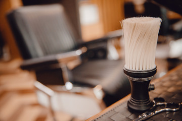 Brush for shaving beard along with bowl, blurred background of hair salon for men, barber shop