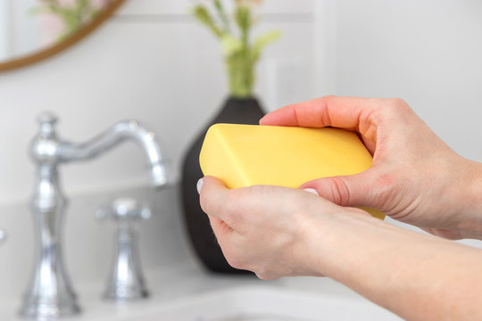 Woman washing her hands with a bar of soap.