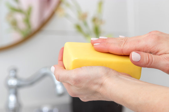 Woman washing hands with a bar of soap.
