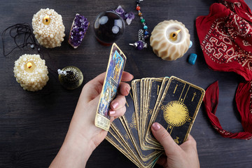 Fortune teller female hands and tarot cards on dark wooden table. Divination concept.