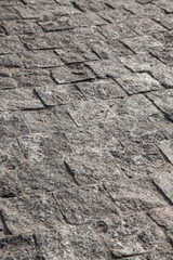 Abstract background of gray cobblestone pavement in light in perspective.
