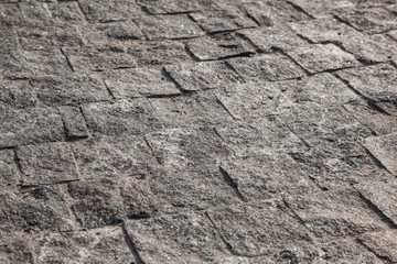 Abstract background of gray cobblestone pavement in light in perspective.