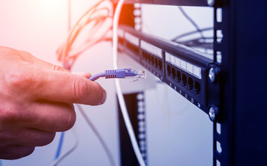 Technician connecting network cables to switches. Connecting cables in server cabinet.