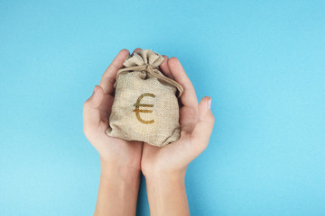 Women hold a money bag on blue background, Saving money for future investment concept.