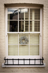 Sash window decorated with a silver Christmas garland in London (UK). Portrait format.