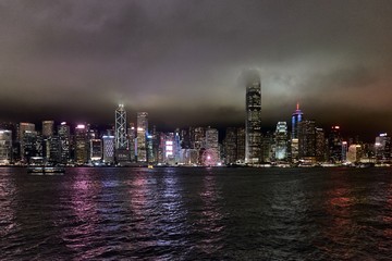 Hong Kong, Victoria harbour - skyline with skyscrapers in the night, cloudy sky