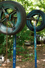 Close-up of a rough home-made simulator from old tires among thick trees in a city park, healthy...
