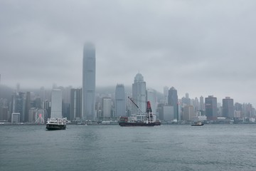 Fototapeta na wymiar 08 03 2019 China, Hong Kong, Victoria Harbour - skyscrapers and passing ships in a cloudy day
