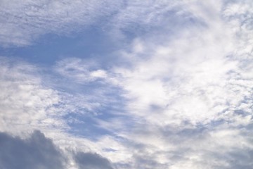 White fluffy clouds against blue sky in bright day for background texture 
