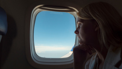 Pensive woman looking out the window of an airplane