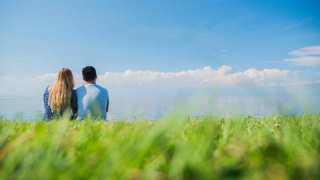 Multi-ethnic couple resting on the green grass, admiring the beautiful nature