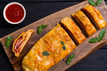 Pizza roll stromboli with cheese salami olives and tomatoes