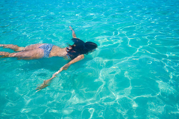 Bikini girl swimming in clear Ibiza beach