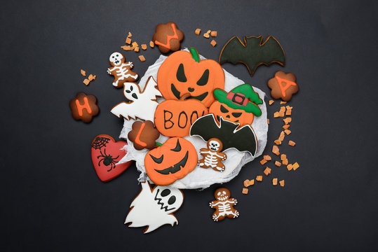 The hand-made eatable gingerbread Halloween pumpkin, ghosts, bat and sceletons on black background