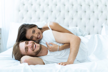 Young happy couple lying together in bed.