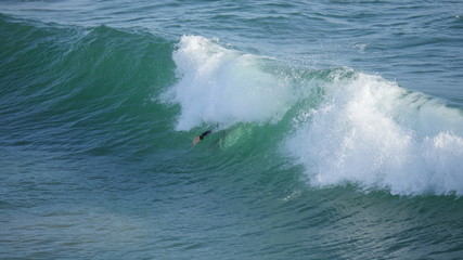 Beach with waves crashing at the ocean with surfer shot in high resolution 4k resolution