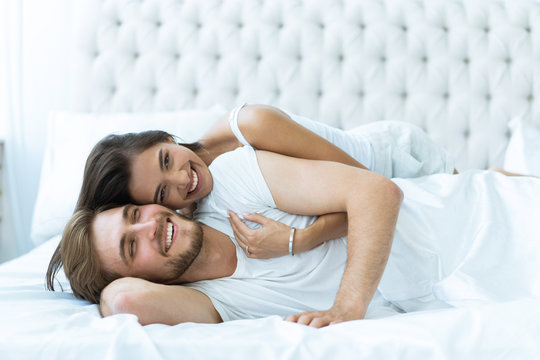 Young happy couple lying together in bed.