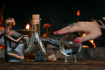 Crystal ball on a wooden table on a burning fire background. Future reading concept.