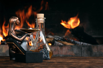 Obraz na płótnie Canvas Alchemist, magician or witch doctor table. Magic potion bottle on a wooden table on a burning fire background. Witchcraft concept.
