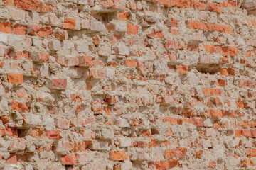 front view of the cracked red clay brick wall of a residential building