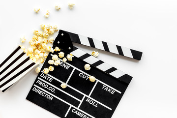 Watch film in cinema with popcorn and clapperboard on white background top view
