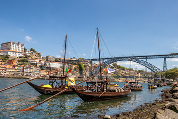 Porto and old traditional boats with wine barrels in Portugal with Dom Luis I Bridge in the background