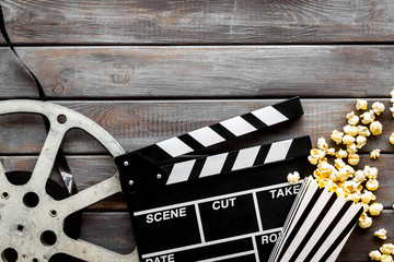 Watch film in cinema with popcorn, video tape and clapperboard on wooden background top view