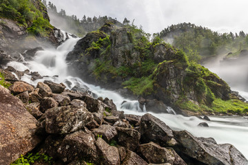 Naklejka na ściany i meble Latefoss waterfalls streams with stones in the foreground, Odda, Hordaland county, Norway