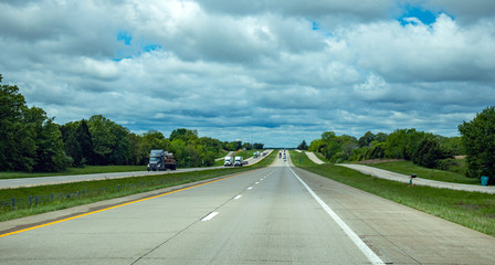 Long highway in the american countryside, blue cloudy sky background