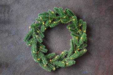 Christmas door wreath made of tree fir branches with xmas lights on dark background.