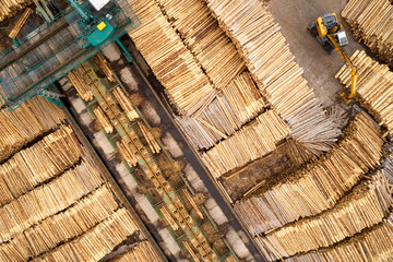 Aerial view of sawmill and chopped tree wood log stacks in a row with machinery