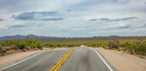 Long highway going down, cloudy blue sky. USA
