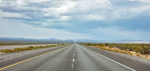 Long highway in the american desert, cloudy blue sky
