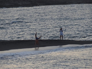 personaje femenino haciendo foto a hombre haciendo piruetas en playa peñon del cuervo malaga © jaime