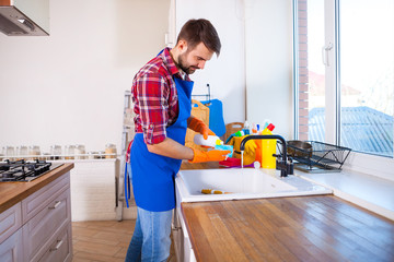 Man makes cleaning the kitchen. Young man washes the dishes. Cleaning concept.
