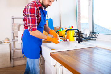 Man makes cleaning the kitchen. Young man washes the dishes. Cleaning concept.