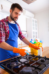 Man makes cleaning the kitchen. Young man washes an oven. Cleaning concept.