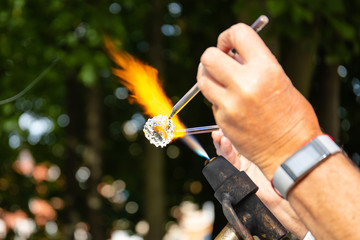 master glass blower makes a craft from molten glass