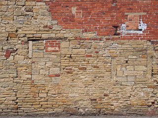 old exterior wall with an irregular patched and repaired brick and stone surface